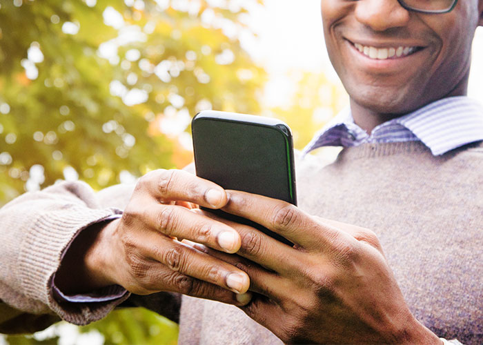 Photo of man using his phone with a smile on his face.