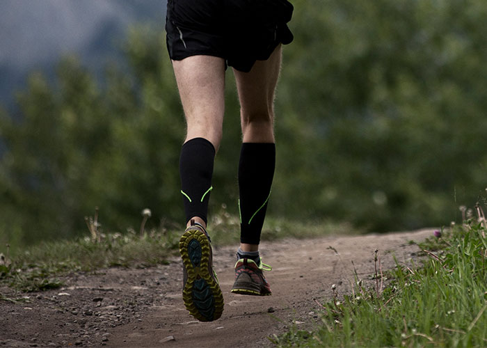 Picture featuring person running on a trail with compression socks on.