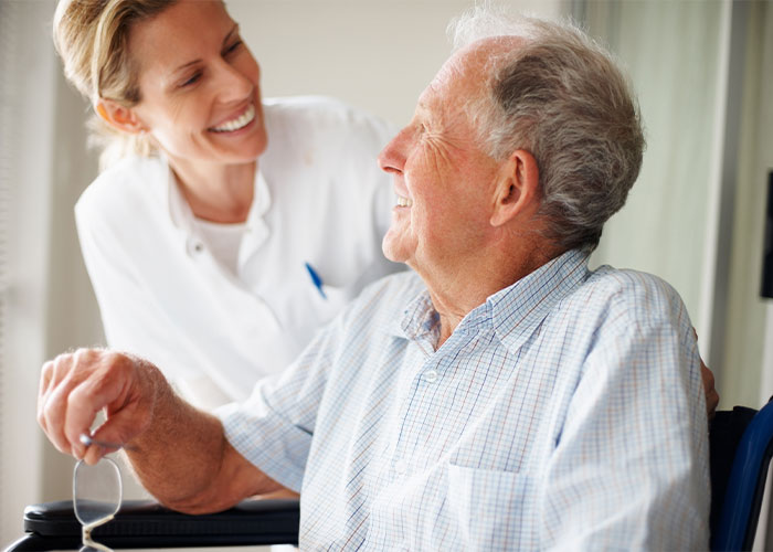 Photo of older man speaking cheerfully with nurse.
